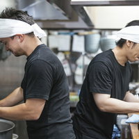ラーメン屋の厨房で汗水たらして働くアルバイトのふたりの写真