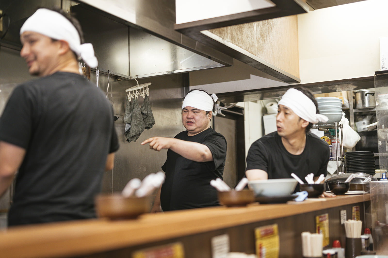 白い帽子とエプロンを着用してラーメン屋の厨房で調理作業をする男性店員［モデル：大川竜弥 段田隼人 Max_Ezaki］