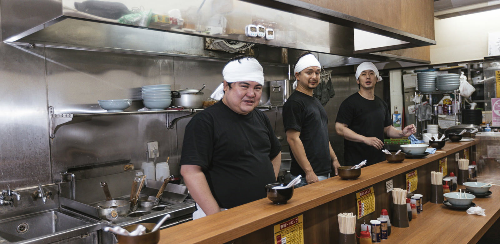 ラーメン屋の厨房で白い帽子をかぶって働く男性店員［モデル：大川竜弥 Max_Ezaki 段田隼人］