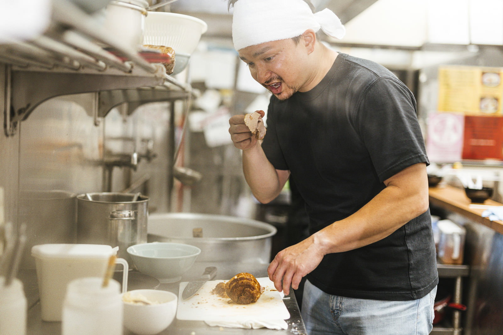 厨房でチャーシューをつまみ食いする白い帽子の外国人男性店員［モデル：Max_Ezaki］