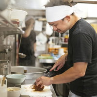 ラーメン屋の厨房でチャーシューを切る店員の写真