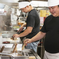 麺の湯で加減をこまめにチェックするラーメン店の男性店員の写真