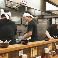 ラーメン厨房で食器を片付ける男性店員の調理場作業の写真