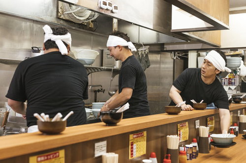 ラーメン厨房で食器を片付ける男性店員の調理場作業
