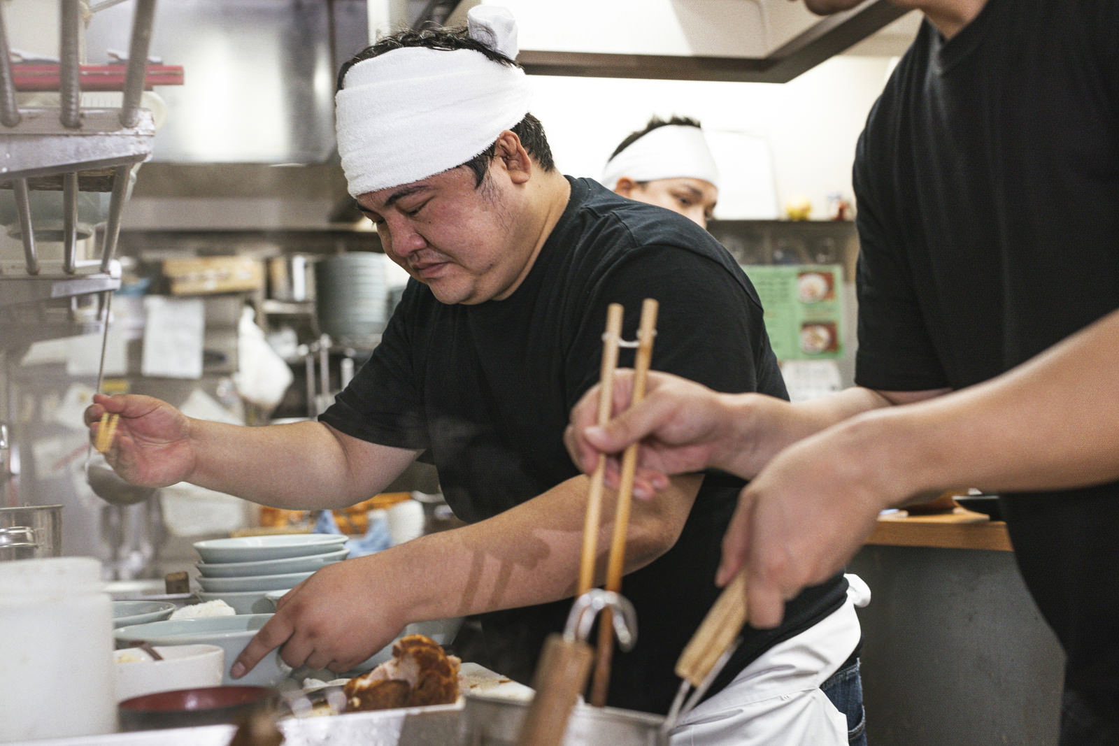 厨房で白い帽子をかぶった男性店員がスープを調理している［モデル：段田隼人］
