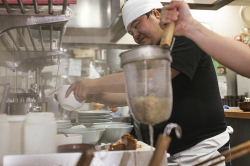湯切りは任せて具をトッピング、ラーメン店主