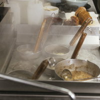 ラーメン屋の厨房で麺を茹でるテボとチャーシューの写真