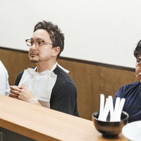 ラーメン屋のカウンター席でメニューをガン見する客たちの写真