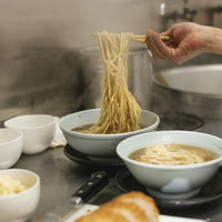 厨房で調理する大ラーメン（麺大盛り）の調理風景の写真