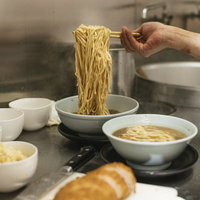 箸で持ち上げた特盛麺、湯気立つラーメン丼のの写真