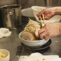 分厚いチャーシューともやし山盛りラーメンを盛り付けるの写真