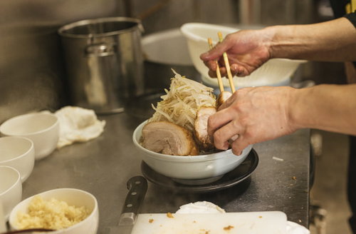 分厚いチャーシューともやし山盛りラーメンを盛り付ける