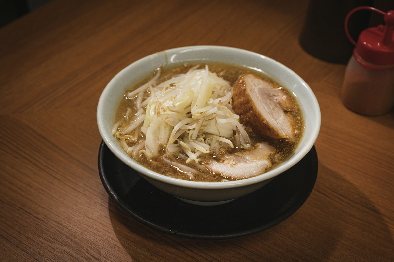 黒い丼に入った醤油ラーメンに白いネギがのせられている