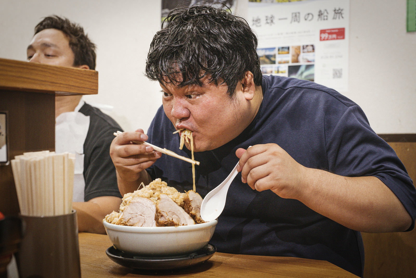 ラーメン店のカウンター席で大盛りのラーメンを食べる男性［モデル：段田隼人］