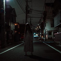 夜の住宅街を歩く不気味なワンピース姿の女性の写真