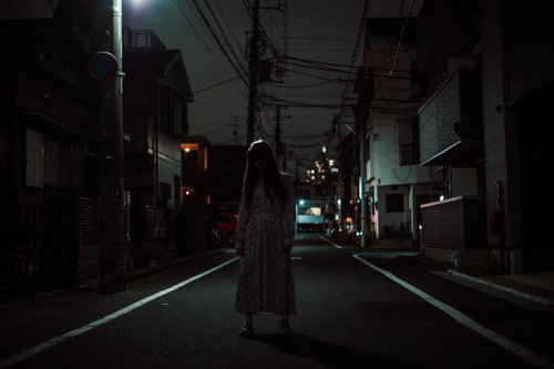 夜の住宅街を歩く不気味なワンピース姿の女性