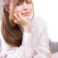 頬杖をついて優しく微笑む茶髪セミロングの女性ポートレートの写真
