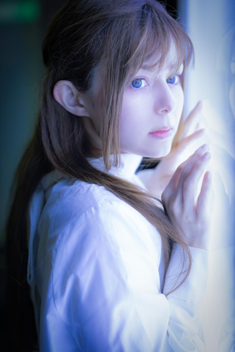 青白い電光に照らされた女性が横向きで構えるポートレート写真［モデル：ラミエル］