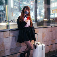 夜の駅前でキャリーケースを持って待ち合わせするハーフの地雷系女子の写真