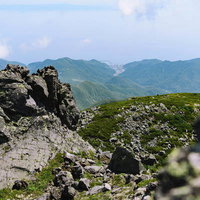 羅臼岳山頂から見下ろす岩場と羅臼の街並みの写真