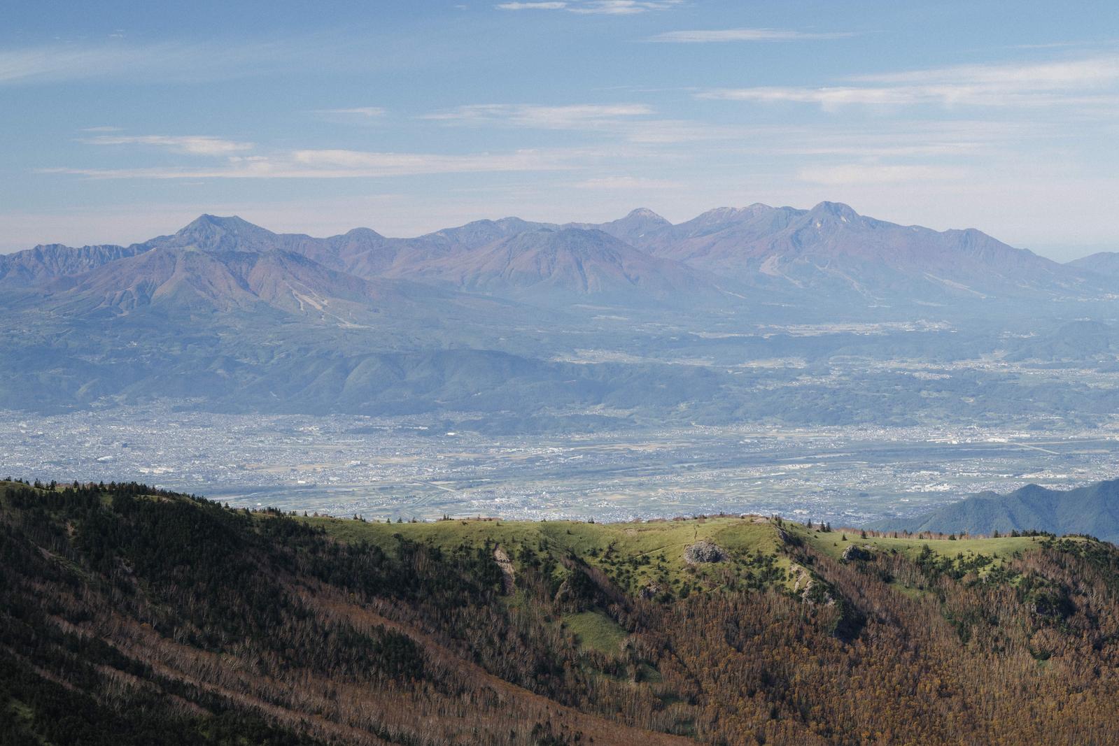 四阿山山頂から北信五岳と麓の街並みを見下ろす景観写真