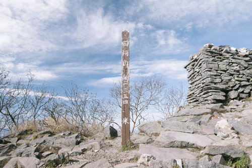 日本百名山の四阿山山頂に立つ木柱と石積み