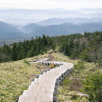 四阿山山頂へ導く木道と遠くかすむ山々の登山風景の写真