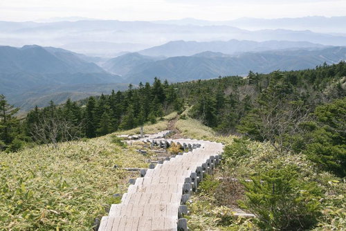 四阿山山頂へ導く木道と遠くかすむ山々の登山風景