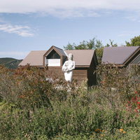 菅平ダボスバス停に立つ女神の彫像と四阿山の景観の写真