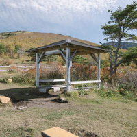 紅葉と青空に囲まれた菅平牧場の東屋と休憩スペースの写真