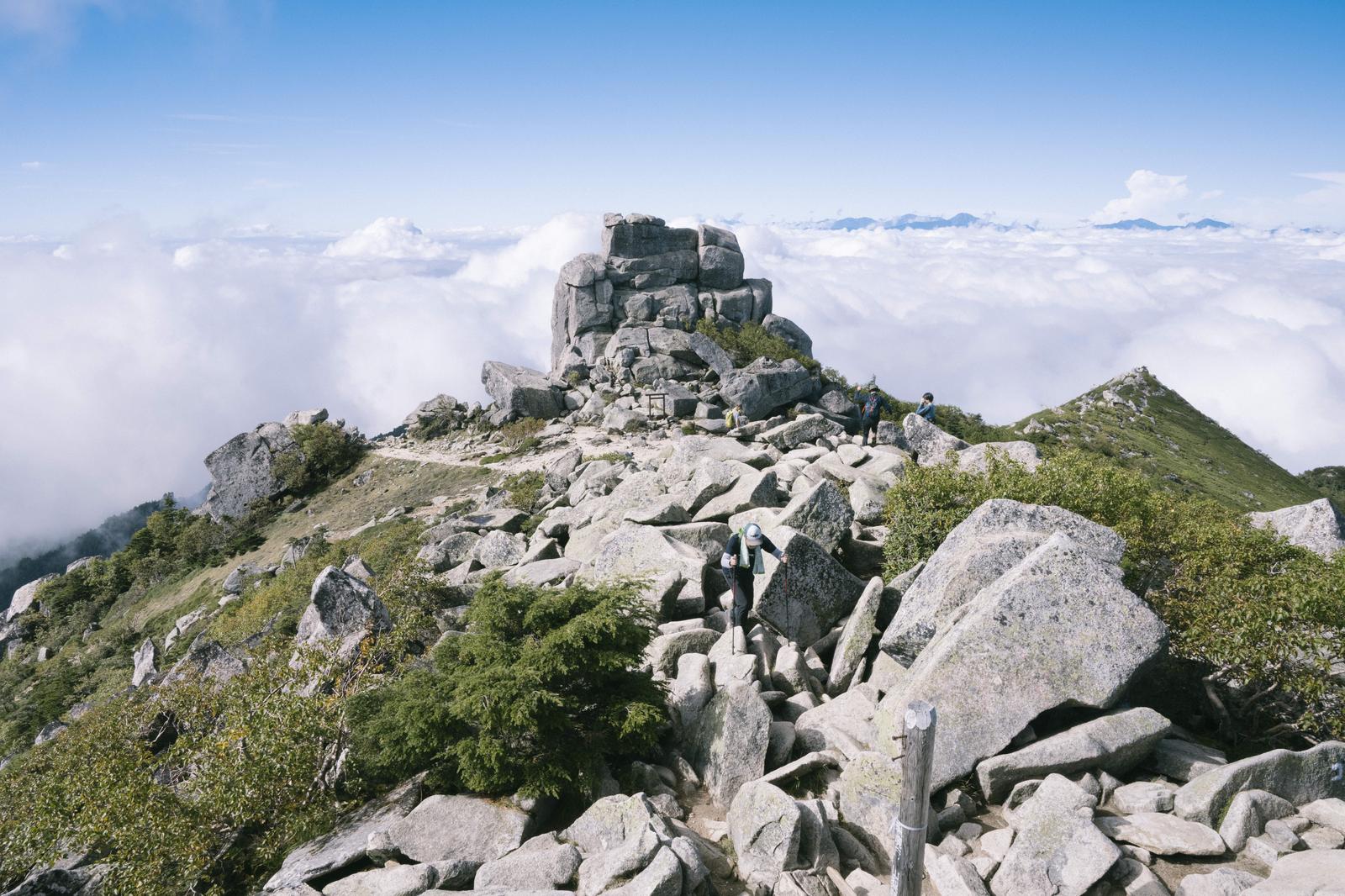 金峰山の五丈岩で雲海越しに山々を眺める登山者たち