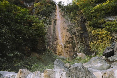 妙高山の岩壁を流れる滝、周囲の緑に囲まれた渓谷