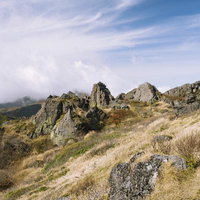 妙高山の山頂部に連なる日本岩と秋の草原・稜線風景の写真