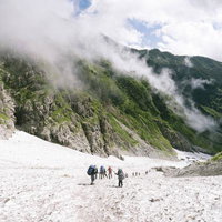 ガスが沸き上がる白馬岳の大雪渓を行く登山者たちの写真