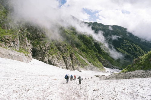 ガスが沸き上がる白馬岳の大雪渓を行く登山者たち