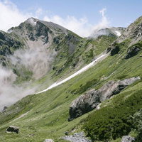 奇岩が転がる稜線と雪渓が残る白馬杓子岳の山肌の写真