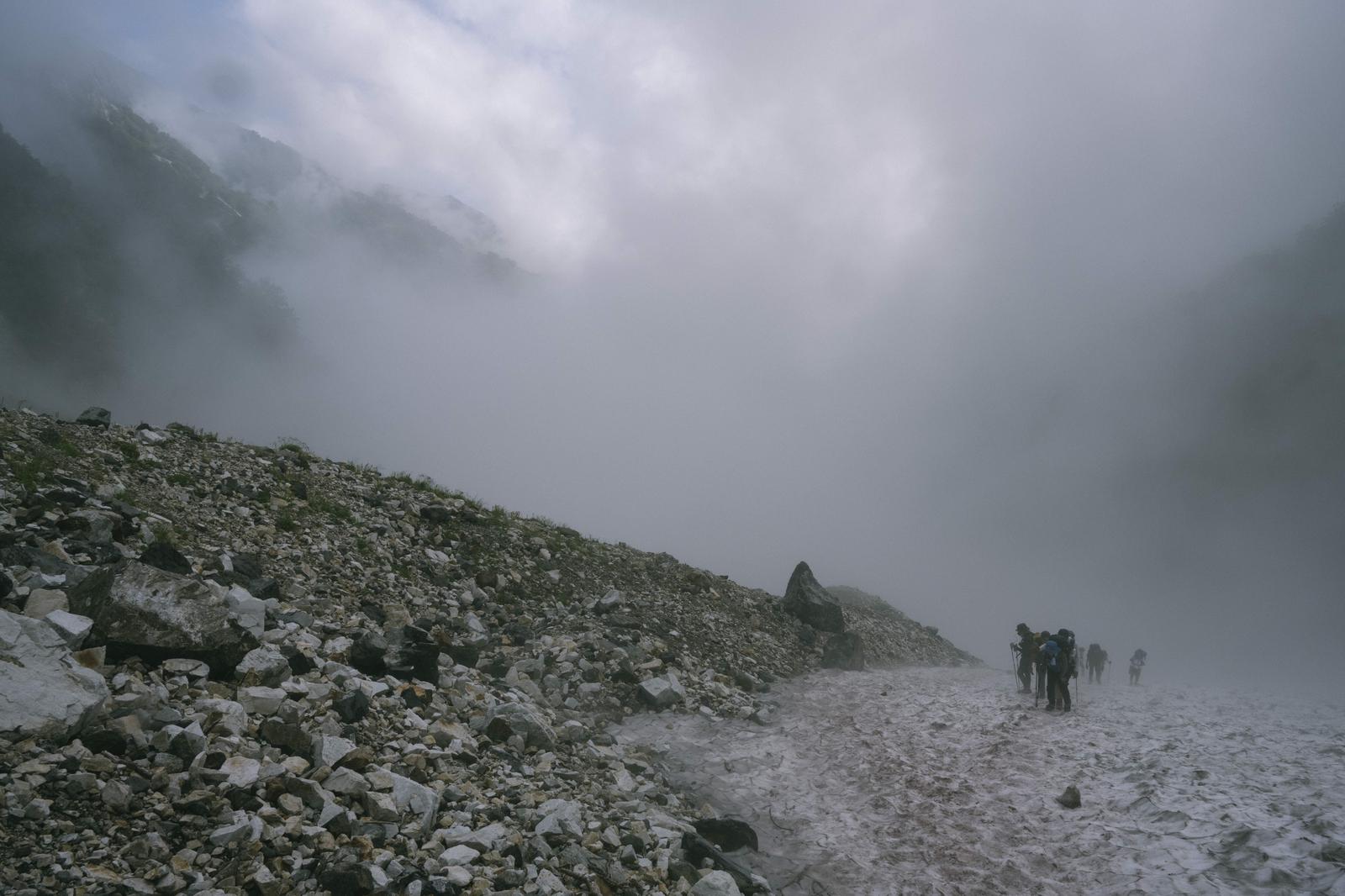 白馬岳の大雪渓でガスに覆われ歩く複数の登山者の様子