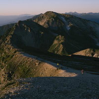 雄大な山脈を背景に白馬岳の稜線を歩むハイカーたちの姿の写真