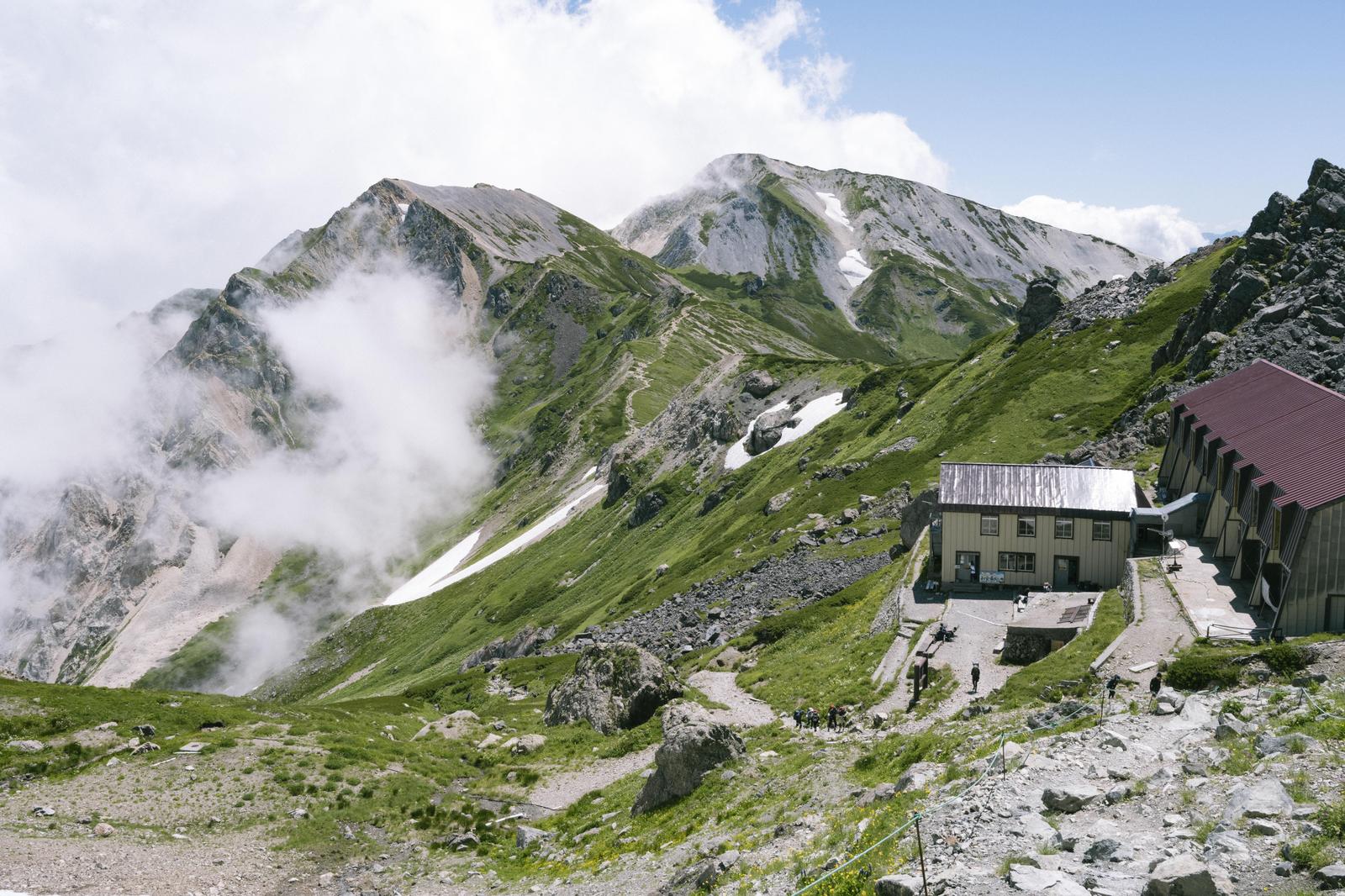 北アルプス白馬岳の頂上付近に建つ山小屋と杓子岳、白馬槍ヶ岳の眺め