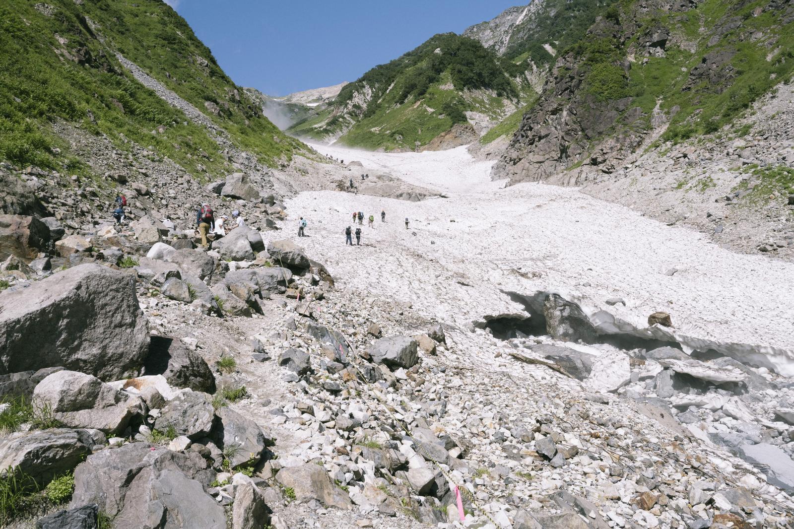 白馬岳の大雪渓で複数の登山者が崩落した白馬尻を歩んでいる風景