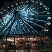観覧車の灯りとともに広がる夜の遊園地の写真
