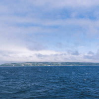 雲の中に隠れた利尻岳と紺碧の海面、北海道の雄大な自然景観の写真