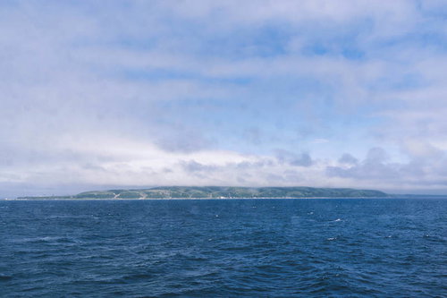 雲の中に隠れた利尻岳と紺碧の海面、北海道の雄大な自然景観