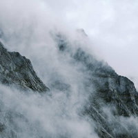 ガスから顔をのぞかせる奥穂高岳の険しい岩肌の写真