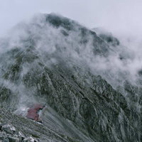 ガスに包まれる穂高岳山荘と奥穂高岳の岩壁の写真