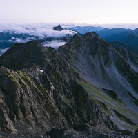 夜明けの奥穂高岳、薄紫の空に浮かぶ岩稜と尾根の写真