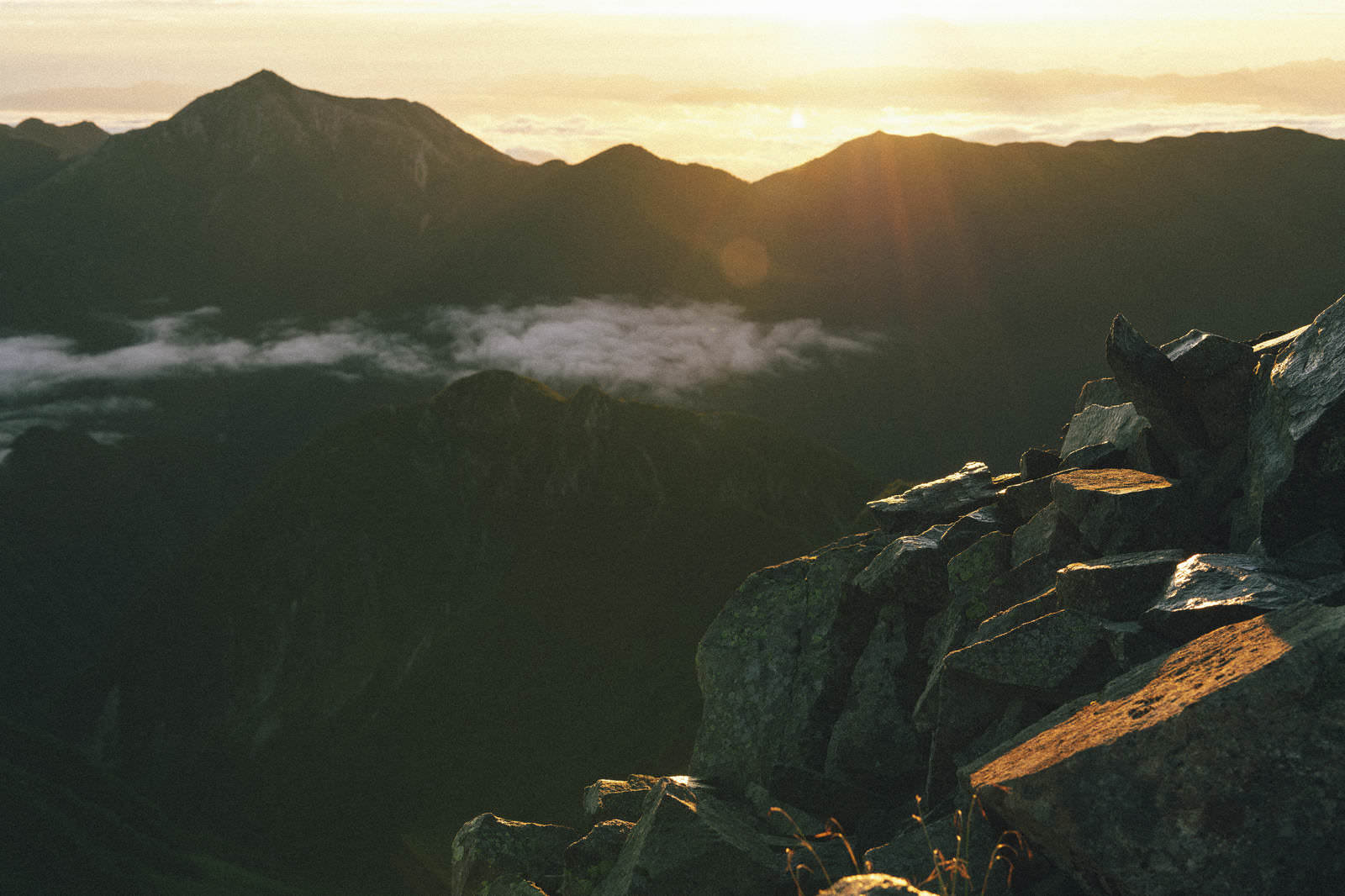 奥穂高岳の岩場から見る朝日と常念岳のシルエット