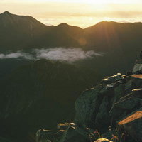 奥穂高岳から見る差し込む朝日と常念岳のシルエットの写真