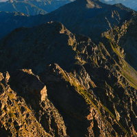 晴れ渡った朝日に照らされる奥穂高岳の稜線の写真