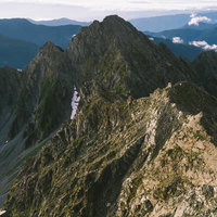 朝日に染まる北アルプスの前穂高岳と奥穂高岳の険しい峰々の写真